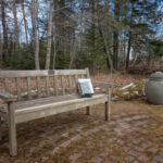 Photo of cedar bench outside Friend Memorial Library in Brooklin, ME with a book on it.
