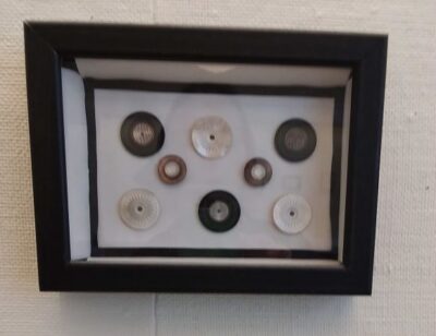 framed collection of eight antique mother of pearl buttons in a black frame