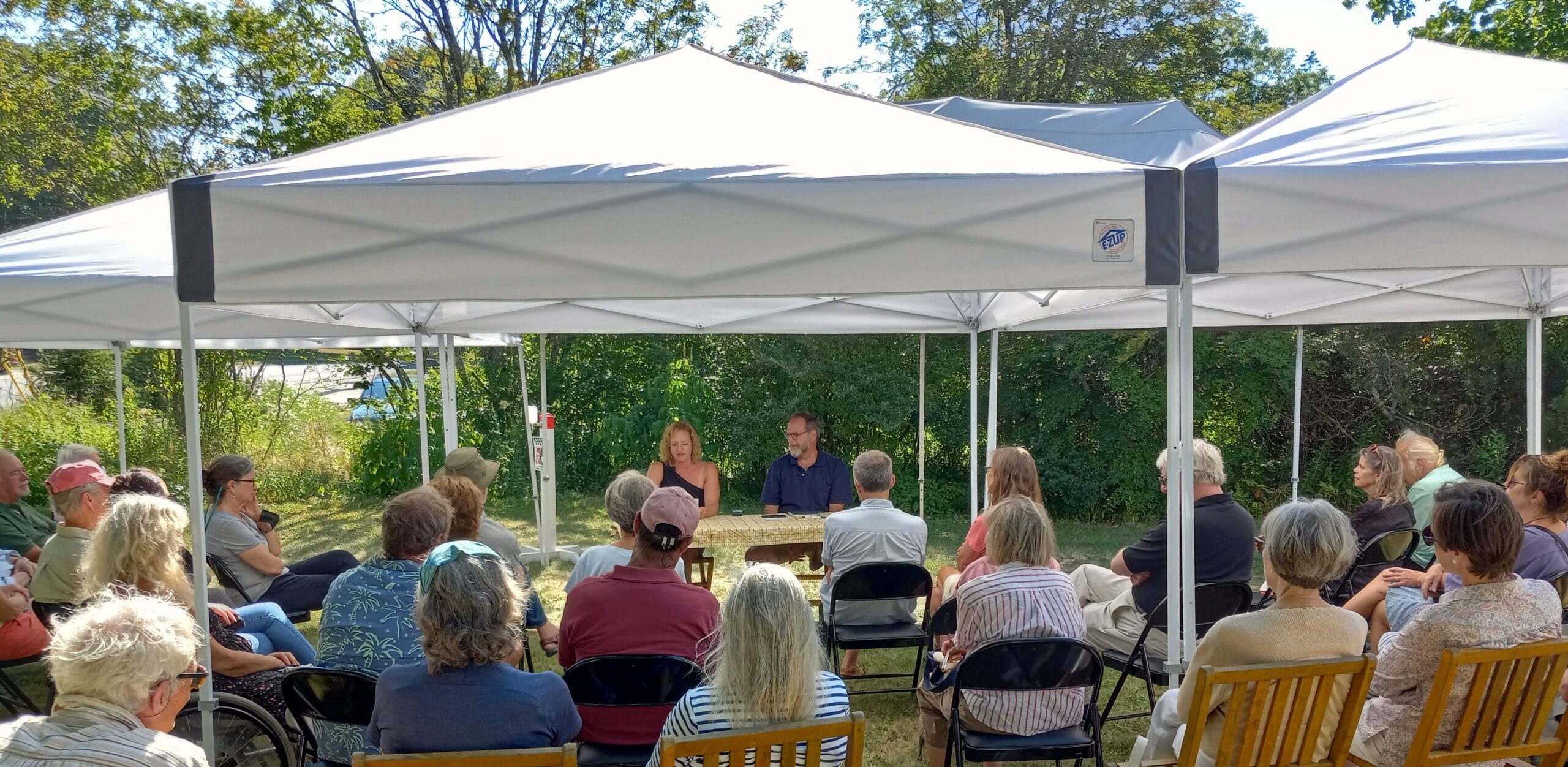 Image of Tents with audience of people at Christine Yurick and David Yezzi Poetry Event at the Friend Memorial Library side yard in August 2022